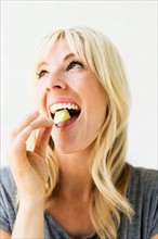 Studio portrait of blonde woman eating bubble gum