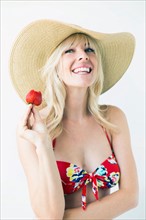 Smiling woman in bikini holding strawberry, studio shot