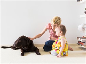 Mother with baby daughter (12-17 months) playing with dog