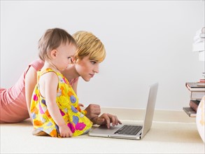 Mother with baby daughter (12-17 months) using laptop