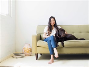 Portrait of woman with dog sitting on sofa