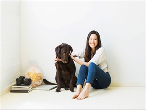 Portrait of woman with dog sitting on floor