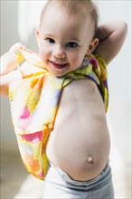 Portrait of girl (12-17 months) showing bellybutton