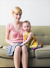 Portrait of mother with daughter (12-17 months) sitting on sofa