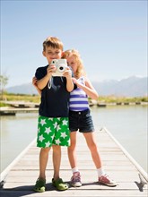 Two kids (4-5, 6-7) holding camera on pier