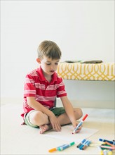 Boy (6-7) sitting on floor and drawing