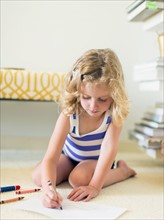 Girl (4-5) sitting on floor and drawing