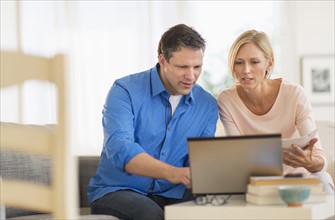 Couple using laptop at home.