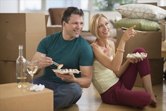 Couple eating sushi in new home.