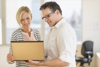 Business man and woman holding laptop.