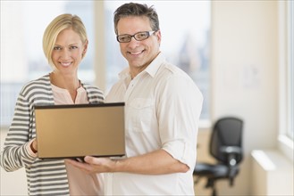 Business man and woman holding laptop.