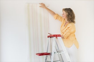 Woman trying out new wallpaper at home.