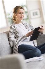 Woman sitting on sofa using tablet pc.