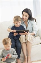 Mother and sons (12-17 months, 6-7) with tablet pc.