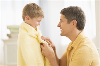 Father with son (6-7) wrapped in towel.