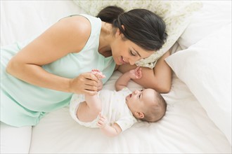 Mother and baby (2-5 months) lying on bed.