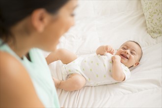 Mother looking at baby (2-5 months) lying on bed.