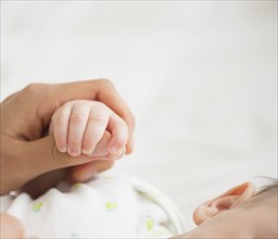 Woman holding baby's (2-5 months) hand.