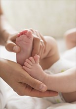 Mother holding feet of baby boy (2-5 months).