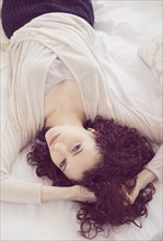 Portrait of beautiful brunette woman lying on bed.