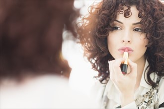 Beautiful brunette woman applying lipstick.