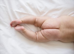 Legs and buttocks of baby girl (2-5 months) lying on bed.
Photo : Jamie Grill