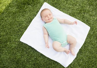 Baby girl (2-5 months) lying on blanket on grass.
Photo : Jamie Grill