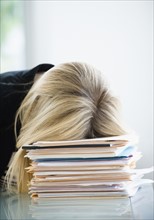 Businesswoman sleeping on stack of files.
Photo : Jamie Grill