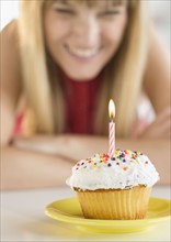 Woman looking at birthday cupcake.
Photo : Jamie Grill
