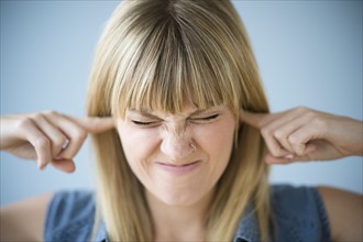 Woman blocking ears with fingers.
Photo : Jamie Grill