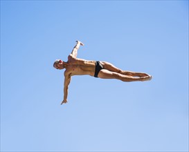 Athletic swimmer mid-air against blue sky.
Photo : Daniel Grill