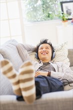 Teenage boy (16-17) lying on sofa and listening to music.
Photo : Daniel Grill