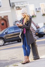 Portrait of woman standing by fire hydrant and text messaging. USA, New York City, Brooklyn,