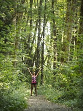 Young women with arms raised in forest. USA, Oregon, Portland.