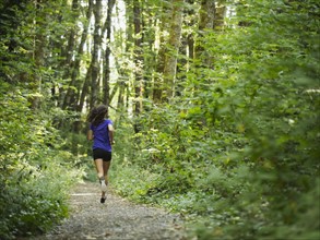 Rear view of young women jogging in forest. USA, Oregon, Portland.