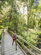 Young woman jogging on footbridge. USA, Oregon, Portland.