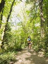 Young woman jogging in forest. USA, Oregon, Portland.