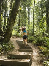 Rear view of young woman jogging in forest. USA, Oregon, Portland.