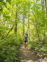 Young woman jogging in forest. USA, Oregon, Portland.