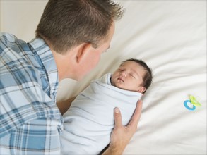 Father holding newborn son (0-11 months).