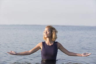 Beautiful woman standing in lake with arms outstretched.
Photo : Jan Scherders