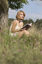 Woman sitting on grass and reading book. Netherlands, Gelderland, Hatertse Vennen.
Photo : Jan