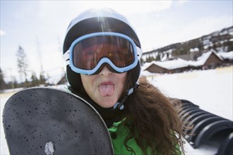 Girl with snowboard sticking out her tongue. USA, Montana, Whitefish.
Photo : Noah Clayton