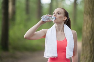 Woman drinking water during jogging in forest. The Netherlands, Erp.
Photo : Mark de Leeuw
