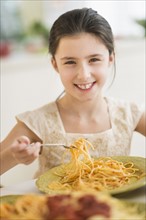 Portrait of girl (8-9) eating pasta.