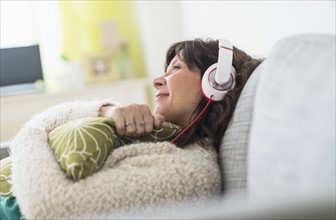 Woman relaxing on sofa, listening to music.