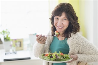 Woman eating salad at home.
