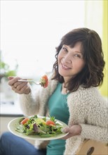 Woman eating salad at home.