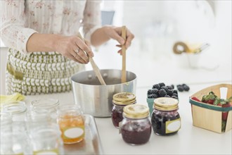 Midsection of woman making preserves in kitchen.
