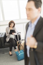 Businessman and businesswoman waiting for flight at airport.